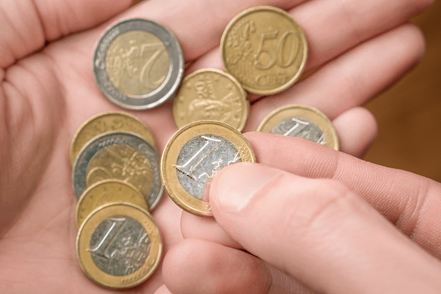 Hand holding several euro coins closely.
