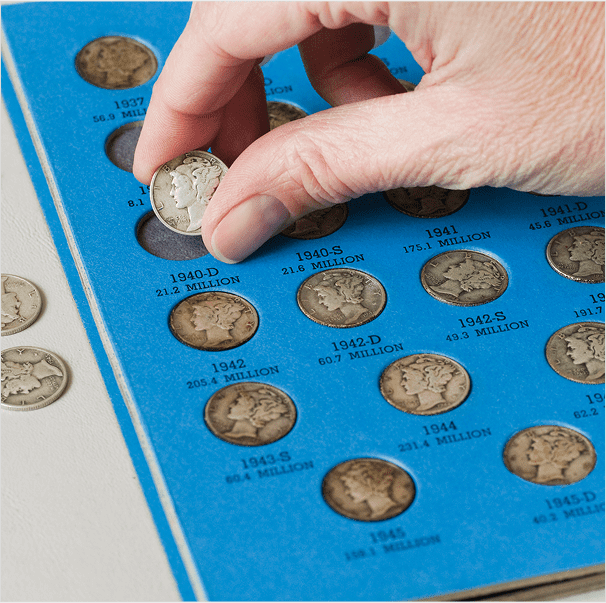 Hand placing coin in blue collection folder.