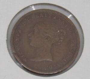 Close-up of an old coin with a queen's profile in a protective case.